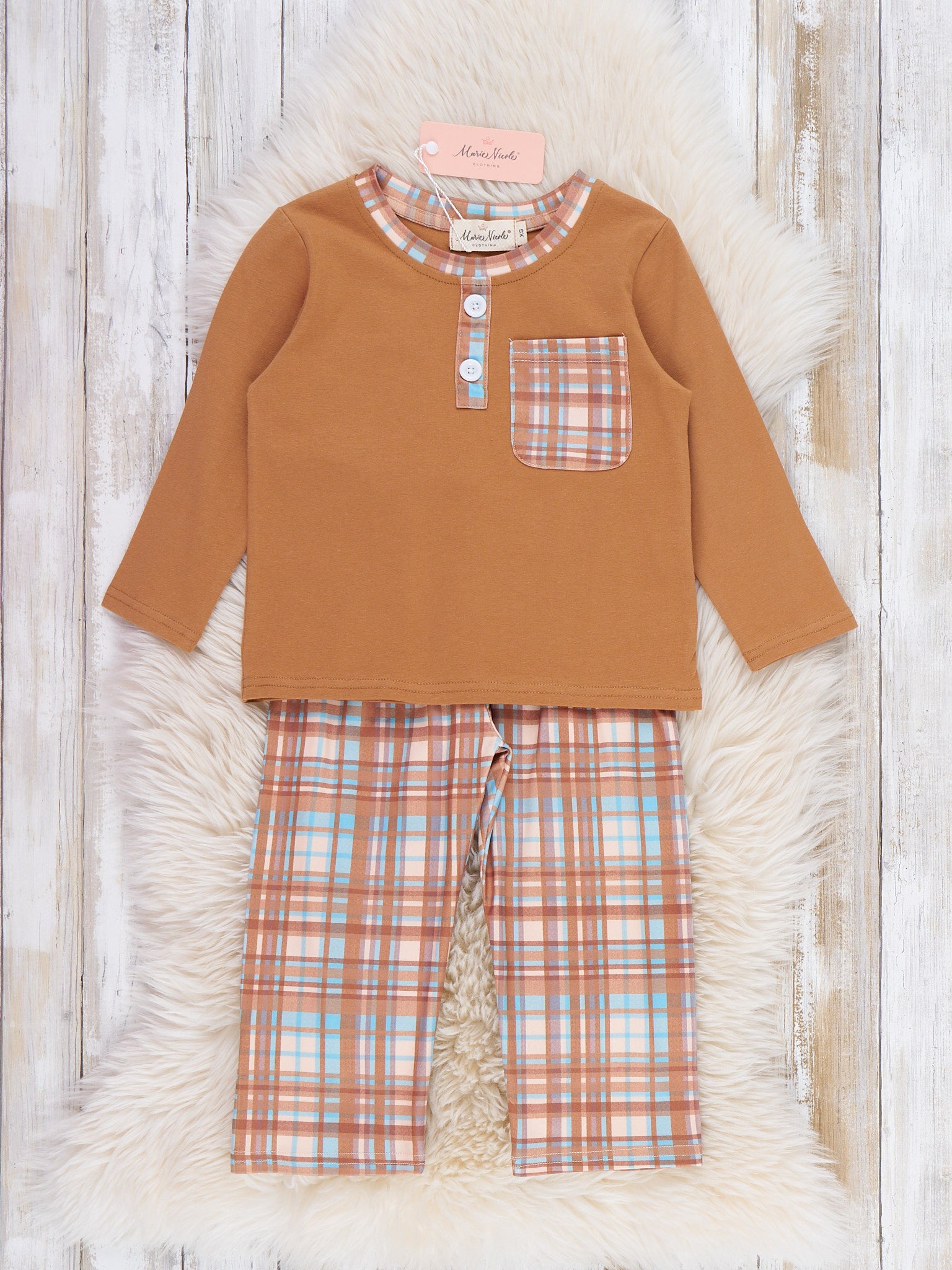 Children's outfit with brown top and plaid pants on a textured white surface