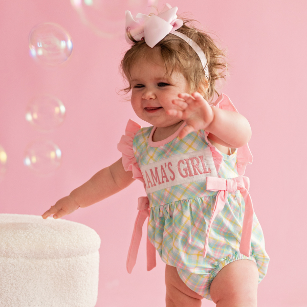 toddler girl wears mama's girl bubble romper against pink background with bubbles near her