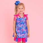 girl wearing purple and pink floral outfit against pink background