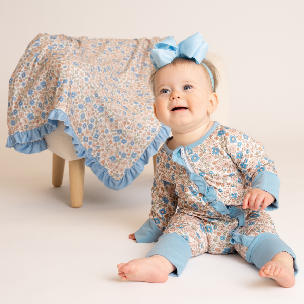 baby wearing a floral fall romper next to matching blanket