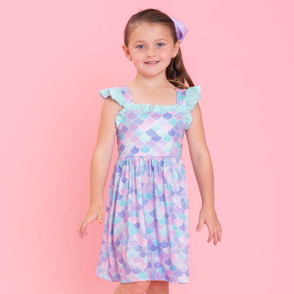 young girl wears graphic dress against pink background