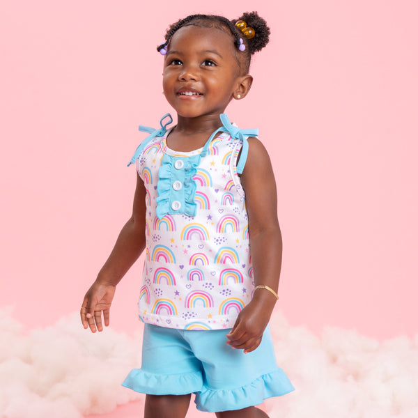 young girl wearing rainbow outfit with pink background